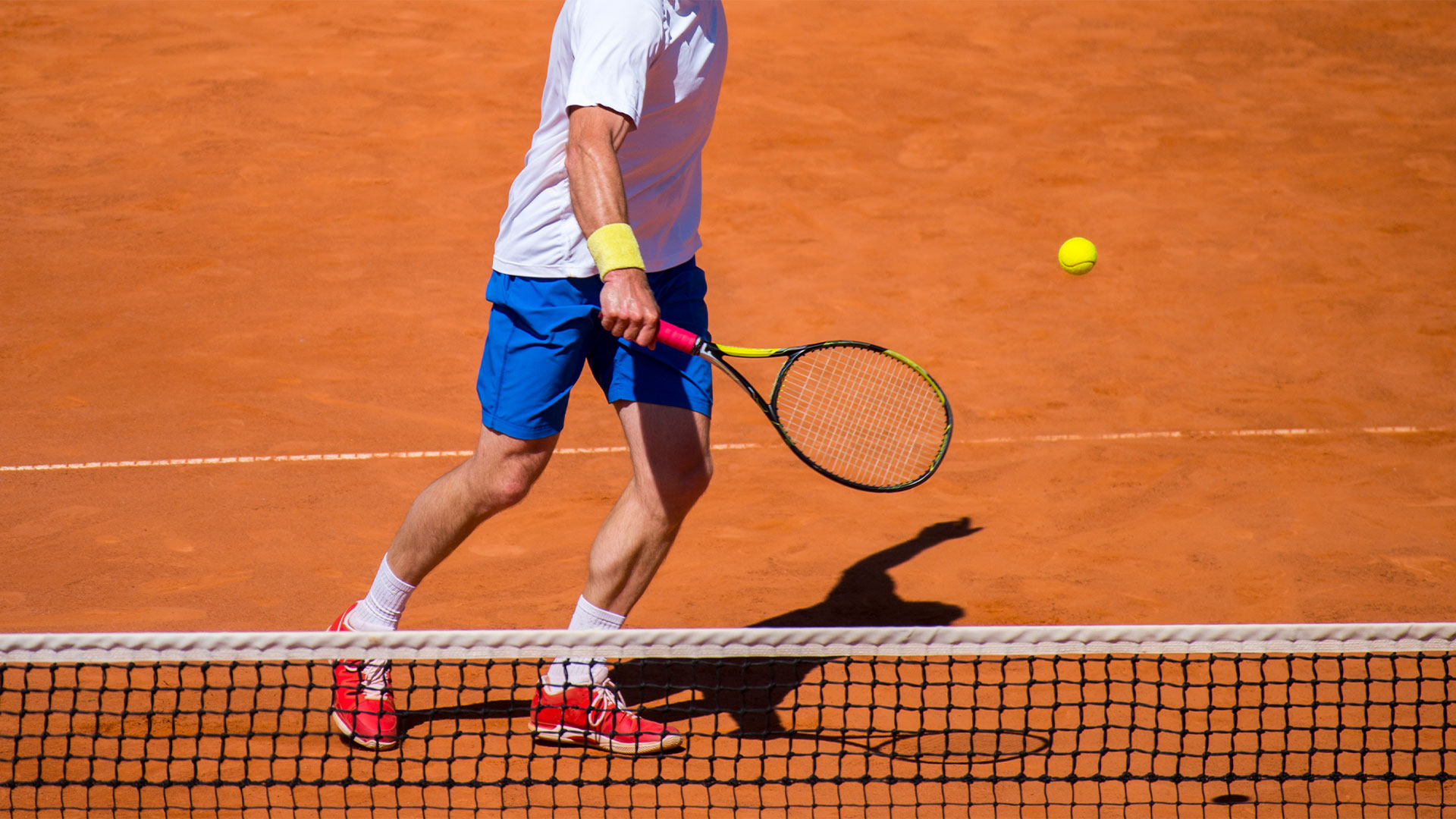 A player volleying at the net on a clay court
